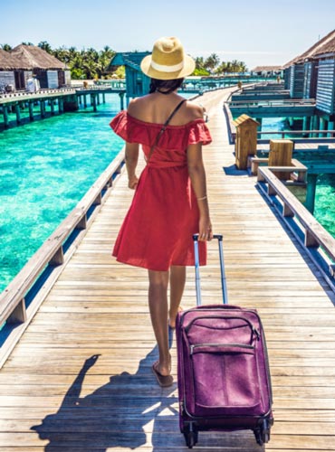 woman with luggage in tropical location overwater walkway